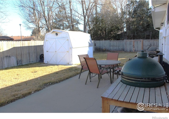 view of patio with a fenced backyard, outdoor dining space, an outbuilding, and a shed