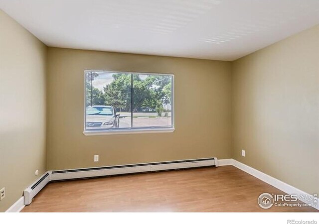 unfurnished room with a baseboard heating unit and light hardwood / wood-style flooring