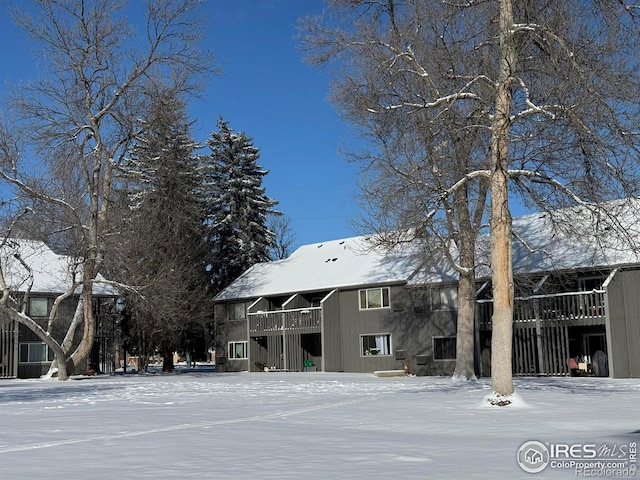 snow covered rear of property featuring a balcony