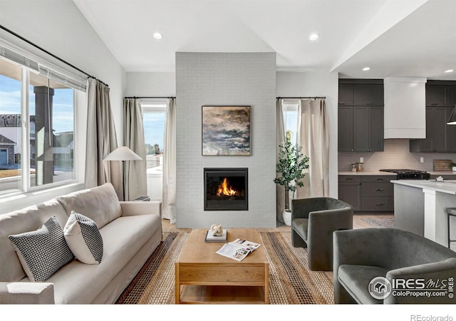 living room featuring light wood-type flooring, lofted ceiling, and a fireplace