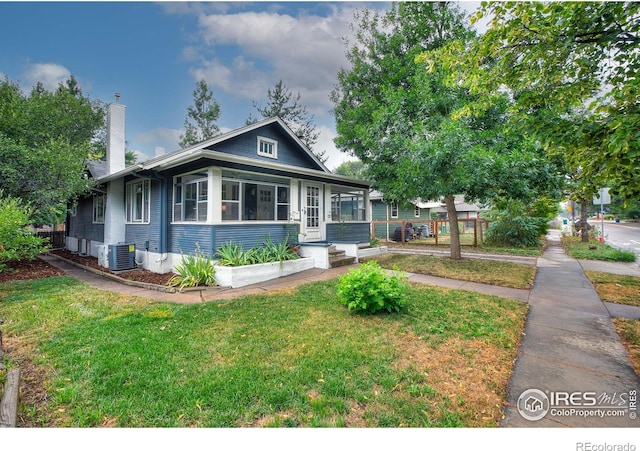 bungalow-style house featuring a front lawn and cooling unit