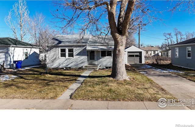 view of front of house featuring a garage, a front lawn, and an outbuilding