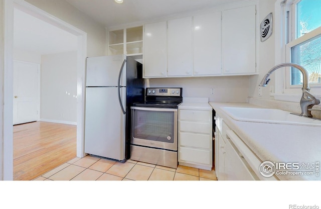 kitchen with light tile patterned floors, white cabinets, appliances with stainless steel finishes, and sink