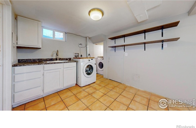 clothes washing area featuring sink, separate washer and dryer, and cabinets