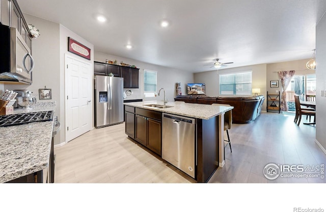 kitchen featuring a center island with sink, ceiling fan, appliances with stainless steel finishes, dark brown cabinetry, and sink