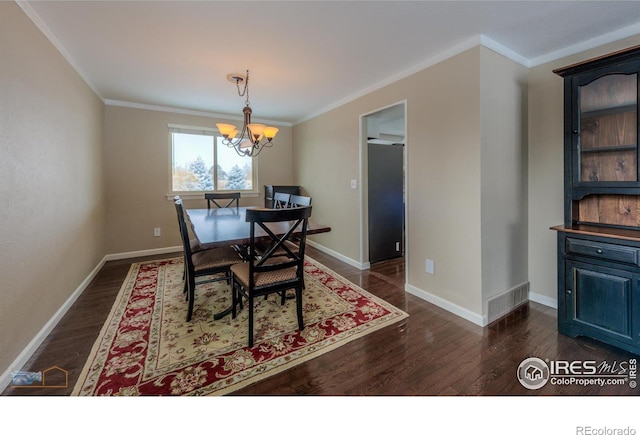 dining area with dark wood-type flooring, crown molding, and a chandelier