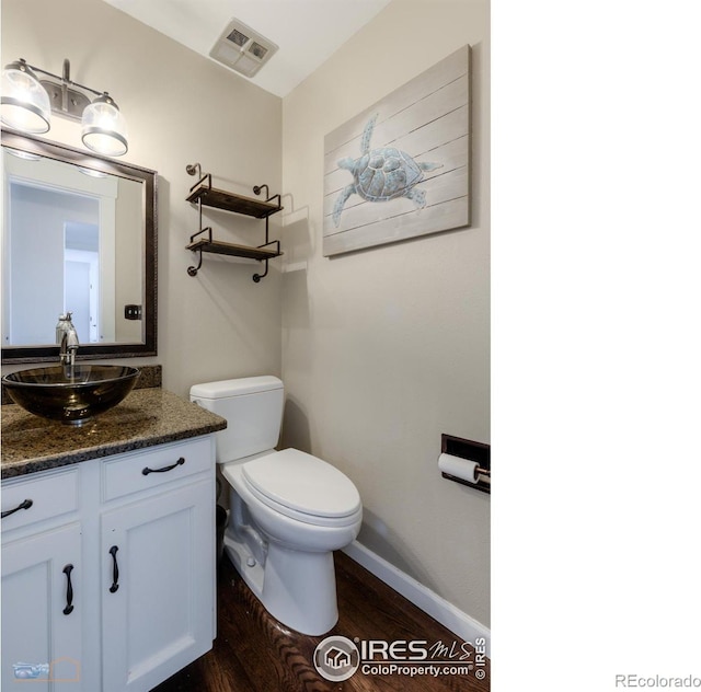 bathroom featuring toilet, vanity, and hardwood / wood-style floors