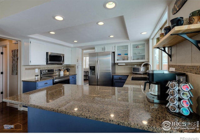 kitchen featuring kitchen peninsula, stainless steel appliances, white cabinetry, and sink