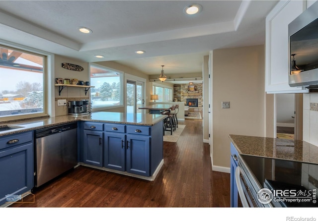 kitchen with plenty of natural light, appliances with stainless steel finishes, blue cabinets, and kitchen peninsula