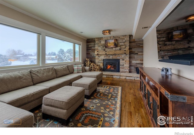 living room with ornamental molding, dark hardwood / wood-style floors, and a stone fireplace