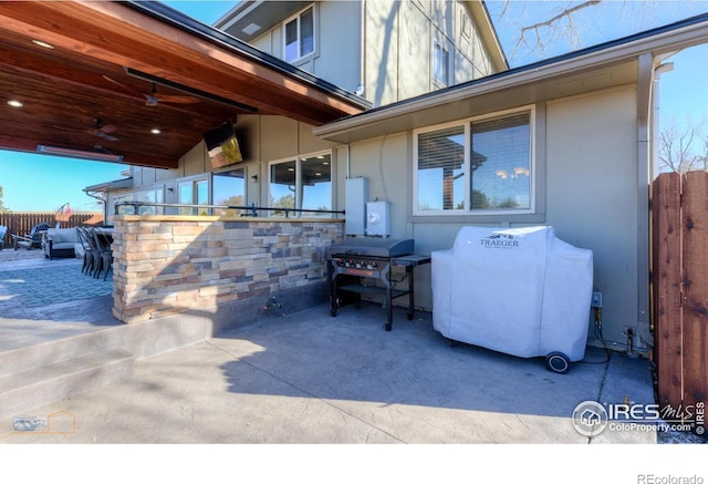 view of patio featuring ceiling fan, a grill, and a bar