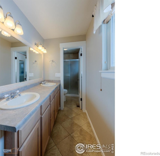 bathroom featuring tile patterned floors, toilet, a shower with door, and vanity