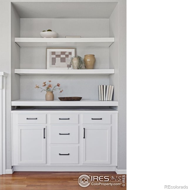 bar with white cabinets and light hardwood / wood-style flooring