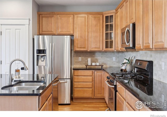 kitchen featuring stainless steel appliances, dark stone countertops, tasteful backsplash, and sink