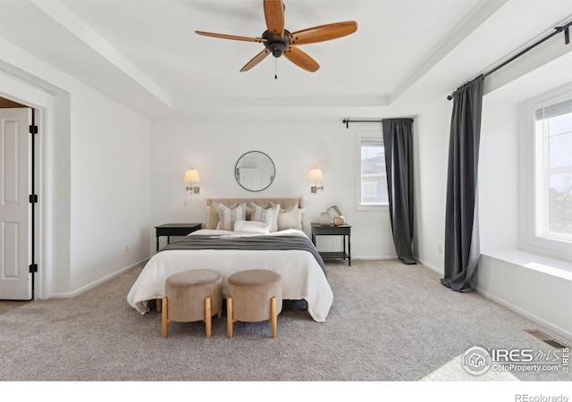 bedroom with ceiling fan, light colored carpet, and a raised ceiling