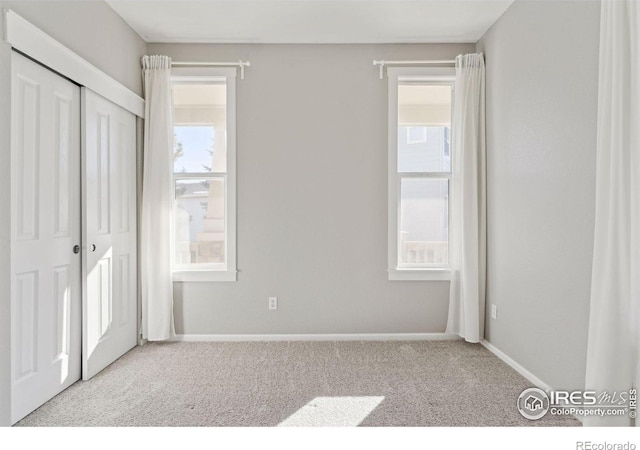 unfurnished bedroom with light colored carpet and a closet