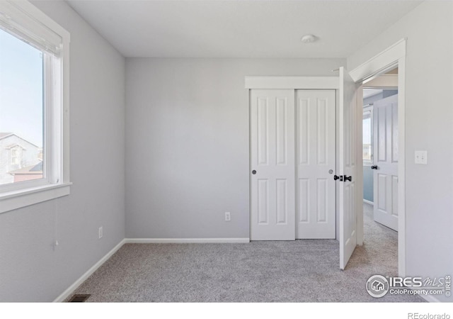 unfurnished bedroom with light carpet and a closet