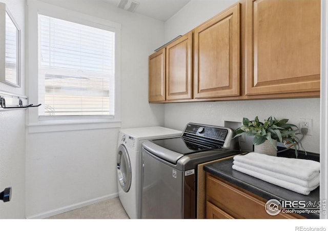 washroom with light tile patterned floors, plenty of natural light, separate washer and dryer, and cabinets