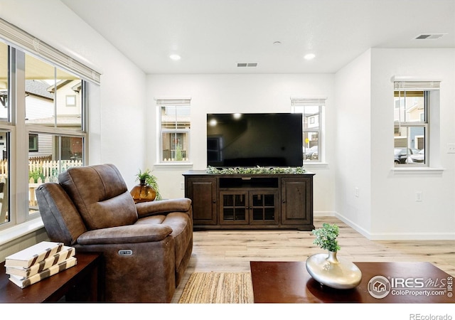 living area with recessed lighting, visible vents, light wood-style flooring, and baseboards