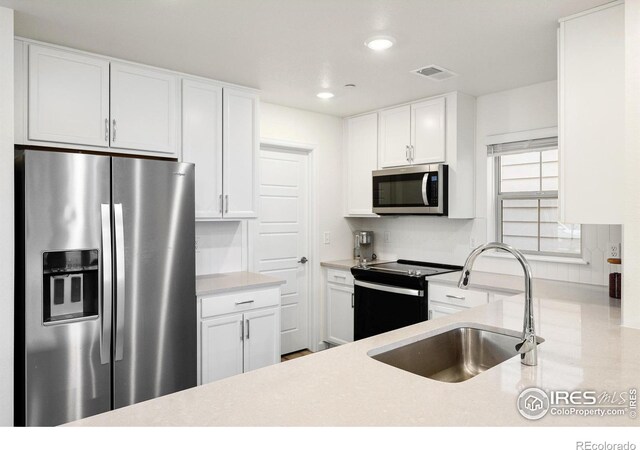 kitchen featuring stainless steel appliances, light countertops, and white cabinets