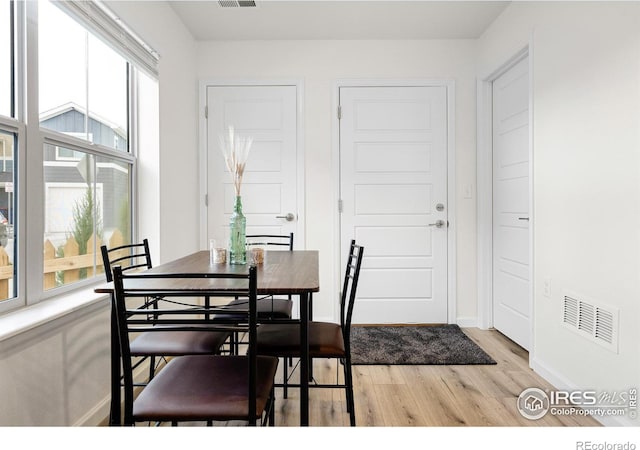 dining area featuring light wood-type flooring, visible vents, and baseboards