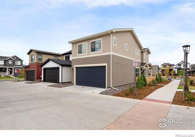 view of front of home with a garage, concrete driveway, and a residential view