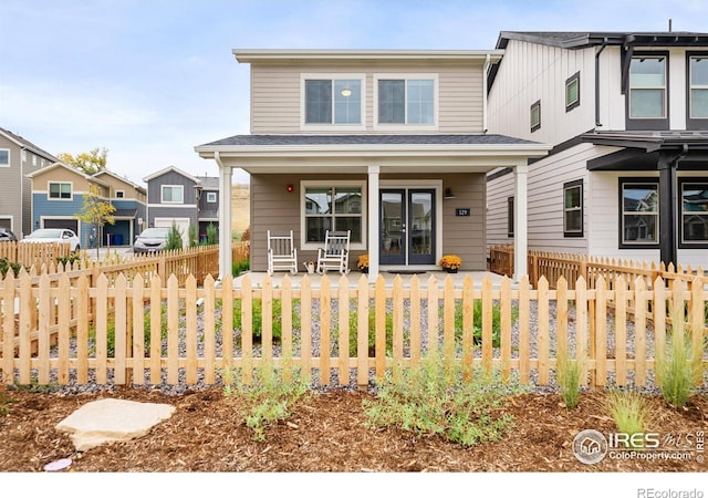 view of front of home featuring a fenced front yard, covered porch, and roof with shingles