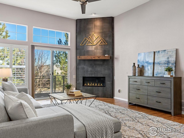 living room with ceiling fan, hardwood / wood-style flooring, and a tile fireplace