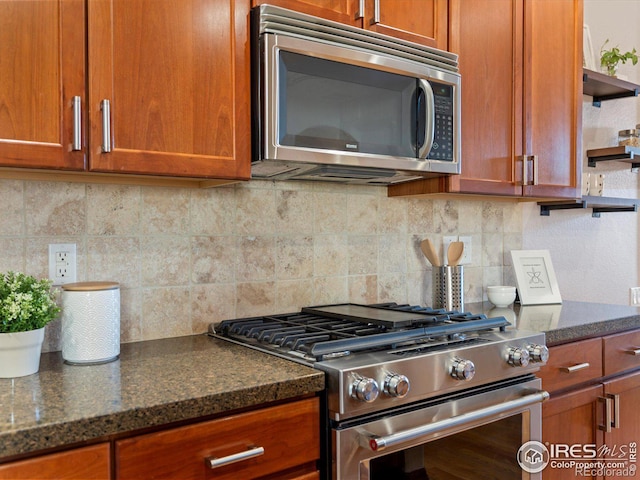 kitchen with appliances with stainless steel finishes, decorative backsplash, and dark stone countertops