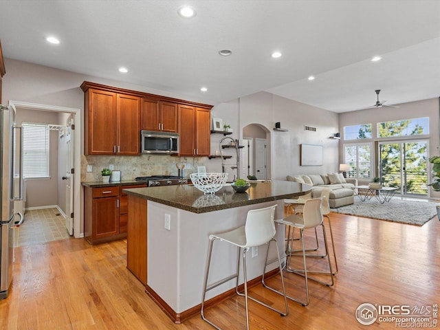 kitchen featuring a kitchen bar, light hardwood / wood-style floors, a center island, and a healthy amount of sunlight