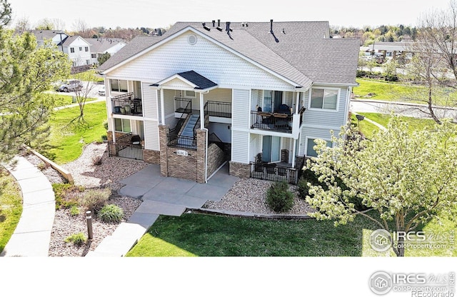 rear view of property featuring a balcony and a yard