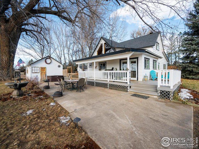 view of front of house with a patio area and an outbuilding