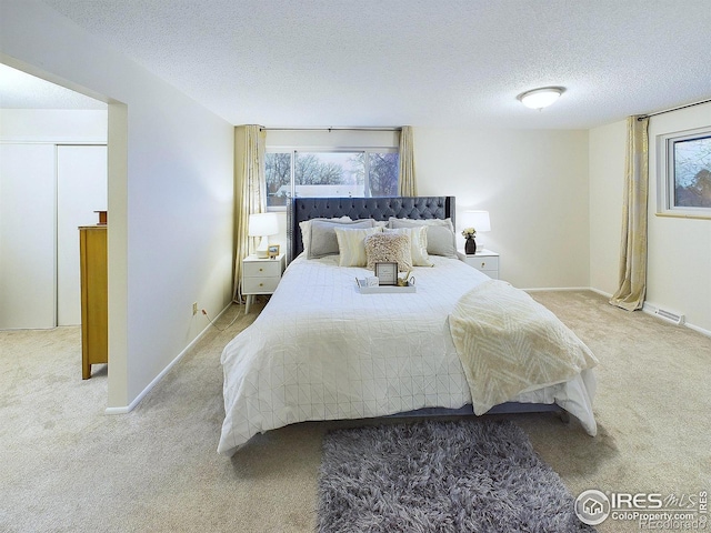 bedroom with multiple windows, carpet floors, and a textured ceiling