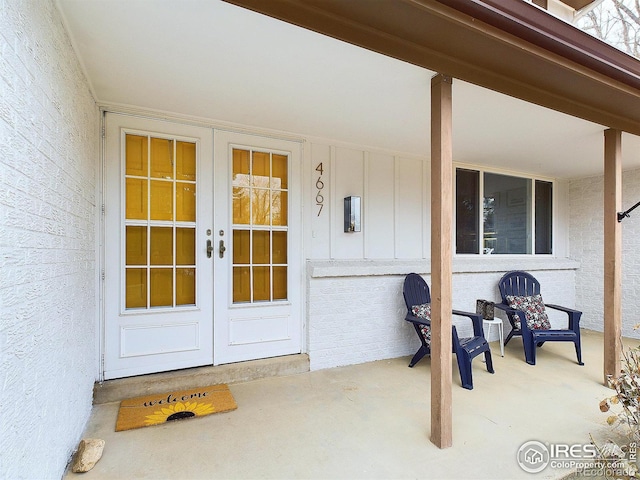 doorway to property featuring french doors, board and batten siding, and stucco siding