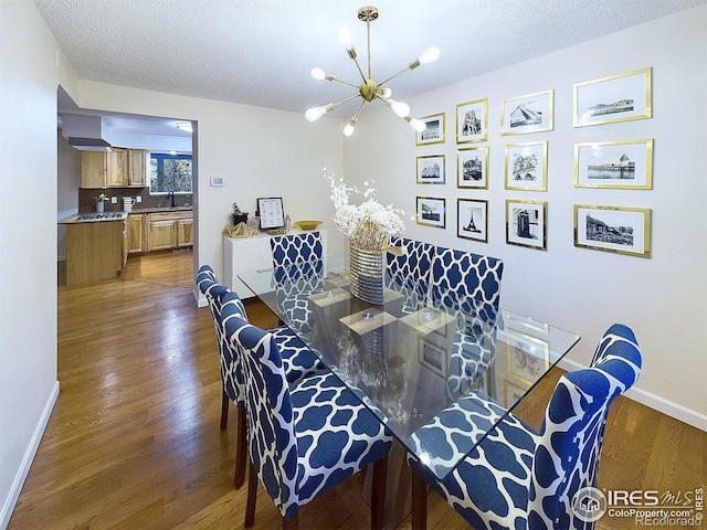 dining area featuring baseboards, a textured ceiling, an inviting chandelier, and wood finished floors