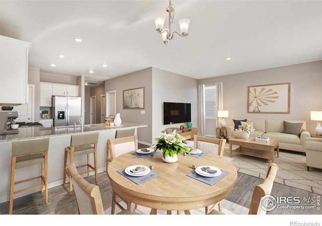 dining space with sink, light hardwood / wood-style flooring, and an inviting chandelier