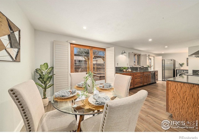 dining space with light wood-type flooring, a textured ceiling, and sink