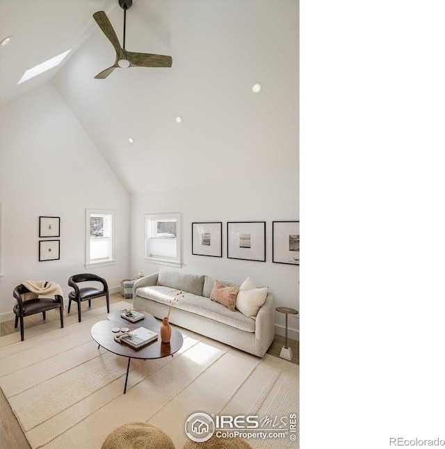 living room featuring light wood-type flooring, ceiling fan, a skylight, and high vaulted ceiling