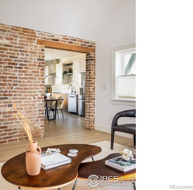 living room with brick wall, wood-type flooring, and sink