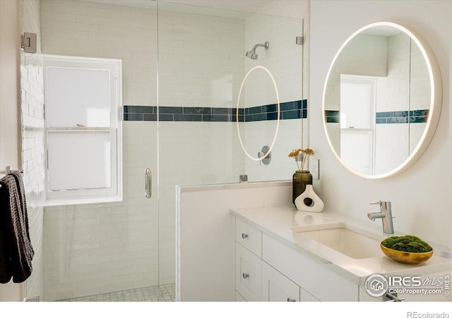 bathroom featuring a shower with shower door and vanity