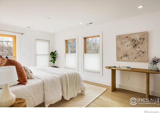 bedroom with multiple windows and light hardwood / wood-style floors