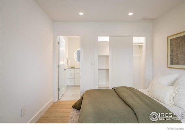 bedroom with ensuite bath, a closet, and light hardwood / wood-style floors