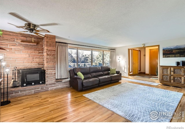 living room with a textured ceiling, ceiling fan, and wood-type flooring