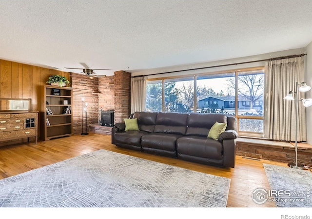 living room featuring a wood stove, plenty of natural light, and light wood-type flooring