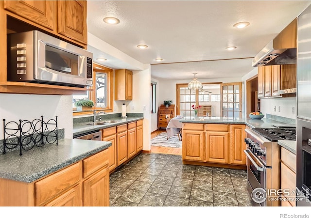 kitchen featuring kitchen peninsula, ventilation hood, stainless steel appliances, pendant lighting, and sink