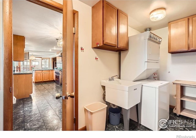 clothes washing area with stacked washer and dryer, cabinets, and sink