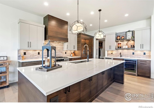 kitchen with white cabinets, beverage cooler, and a center island with sink