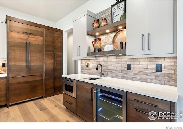 bar featuring white cabinets, sink, backsplash, and beverage cooler