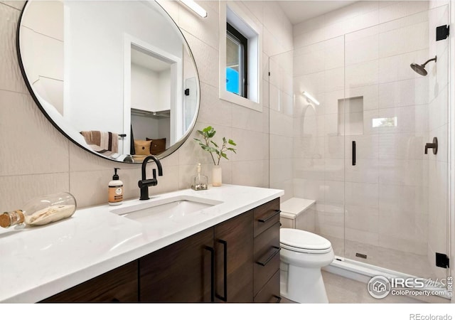 bathroom with tasteful backsplash, vanity, tile walls, toilet, and an enclosed shower