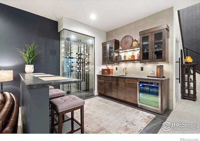 bar featuring sink, dark brown cabinets, and wine cooler